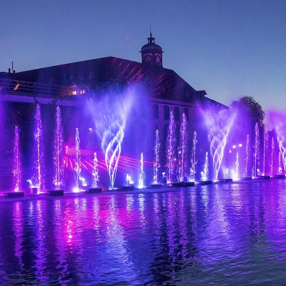 Thuner Wasserzauber mit violetten Lichtern und dem Hotel Freienhof