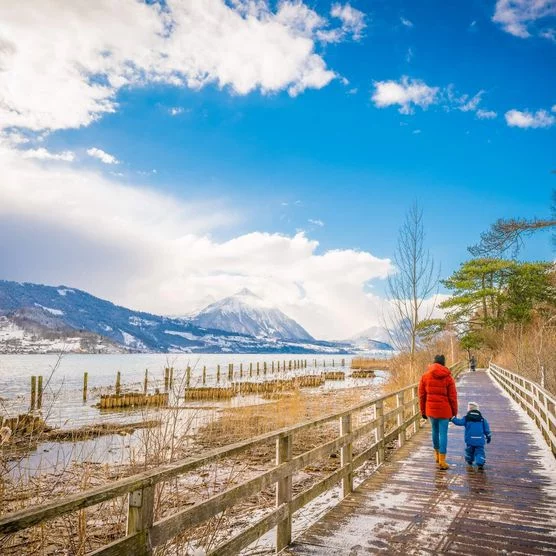 Familie spaziert an einem Wintertag über den Holzsteg entlang des Thunersees