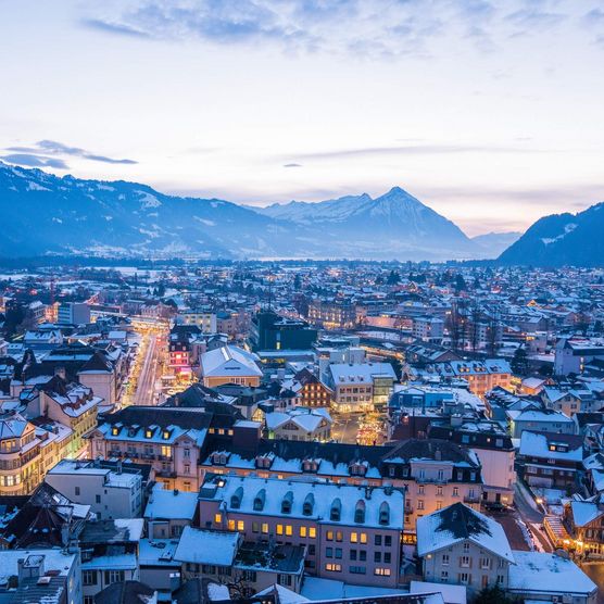 Luftnahme von Interlaken mit Stadtlichtern in der winterlichen Abenddämmerung