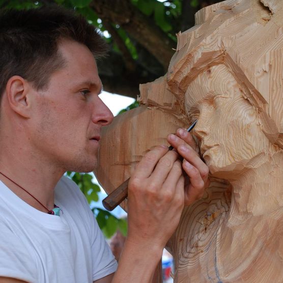 Ein Holzbildhauer schnitzt an seiner Skulptur am Holzbildhauer Symposium in Brienz