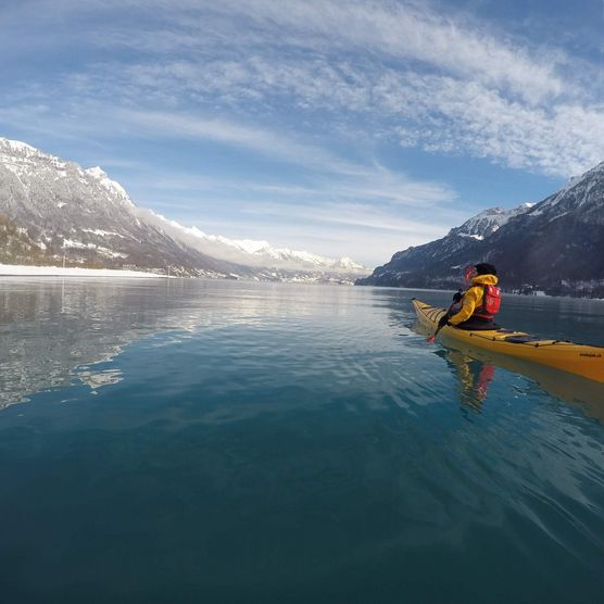 Der Brienzersee im Winter mit verschneiten Bergen und einem gelben Kajak