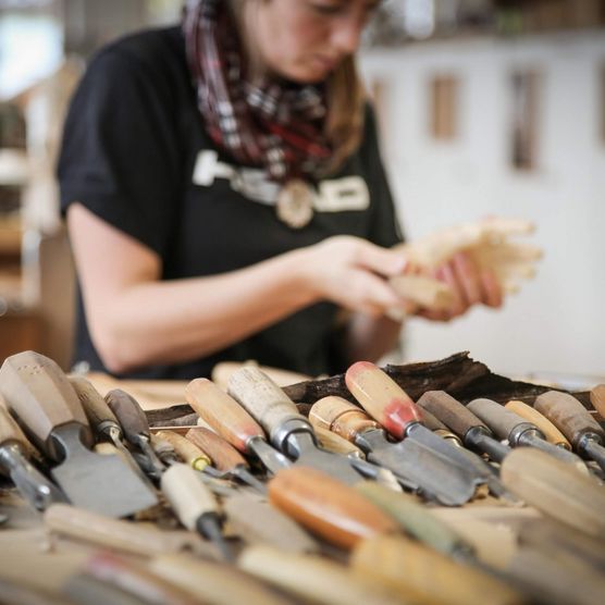 Verschiedene Werkzeuge für die Holzschnitzkunst in der Schule für Holzbildhauerei in Brienz. Im Hintergrund eine Schülerin.