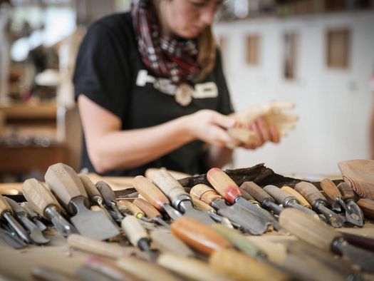 Verschiedene Werkzeuge für die Holzschnitzkunst in der Schule für Holzbildhauerei in Brienz. Im Hintergrund eine Schülerin.