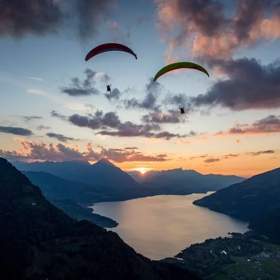 Paraglider an einem Herbstabend bei Sonnenuntergang in luftiger Höhe oberhalb von Interlaken