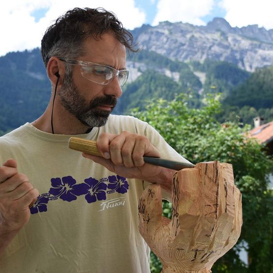 Holzbildhauer bearbeitet seine Skulptur 