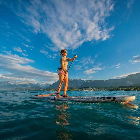 Eine Frau paddelt auf dem Stand Up Paddle bei Sonnenuntergang