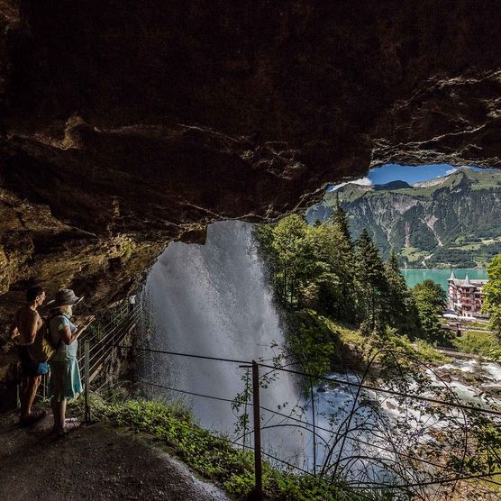 Ein Paar bestaunt von einer Höhle aus die tosenden Wassermassen der Giessbachfälle