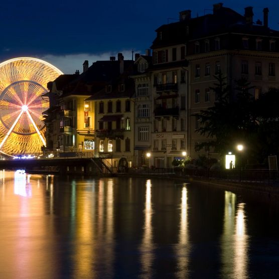 Riesenrad spiegelt sich mit Lichtern in der Aare in Thun