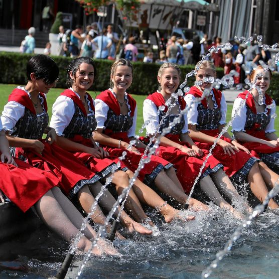 Ehrendamen baden ihre Füsse im Brunnen am Unspunnenfest in Interlaken