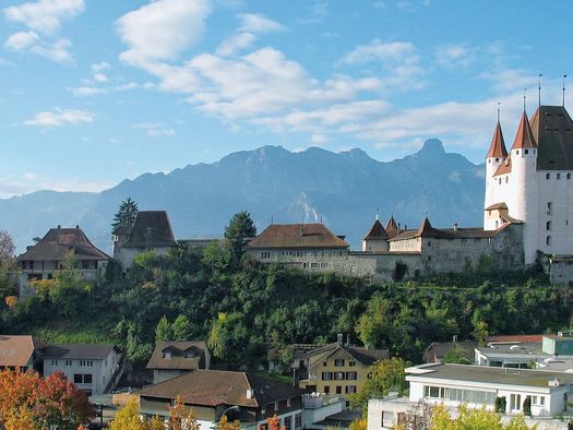 Der Schlossberg mit dem weissen Schloss Thun und der Schlosskirche sowie die Berge im Hintergrund