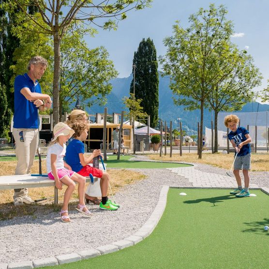 Familie spielt an einem Frühlingstag Minigolf auf der Minigolf Open Standard Anlage in der Spiezer Bucht